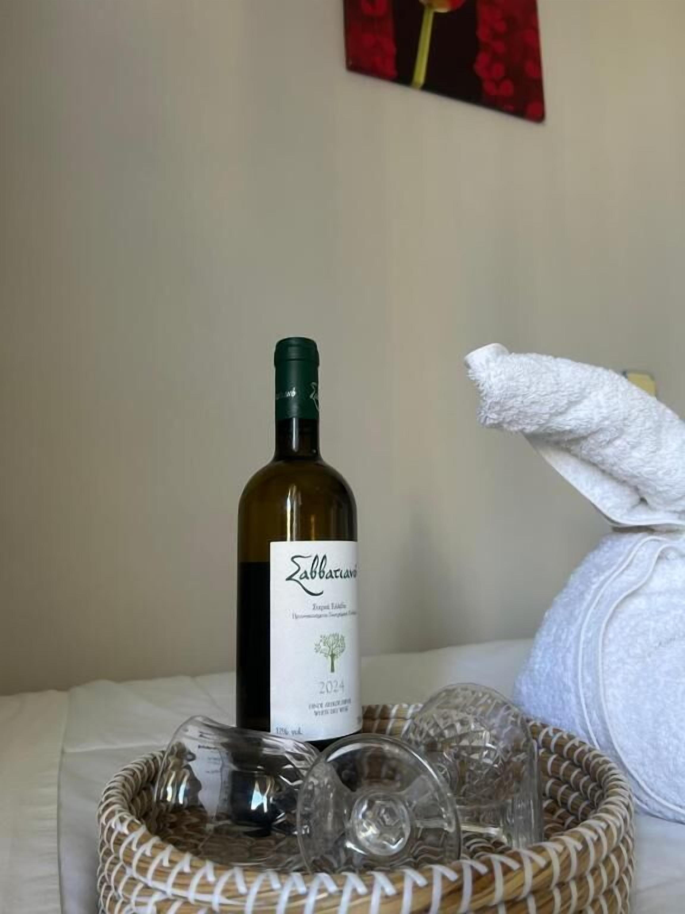 Una bottiglia di vino Zabbara, un asciugamano bianco e bicchieri trasparenti su un tavolo.