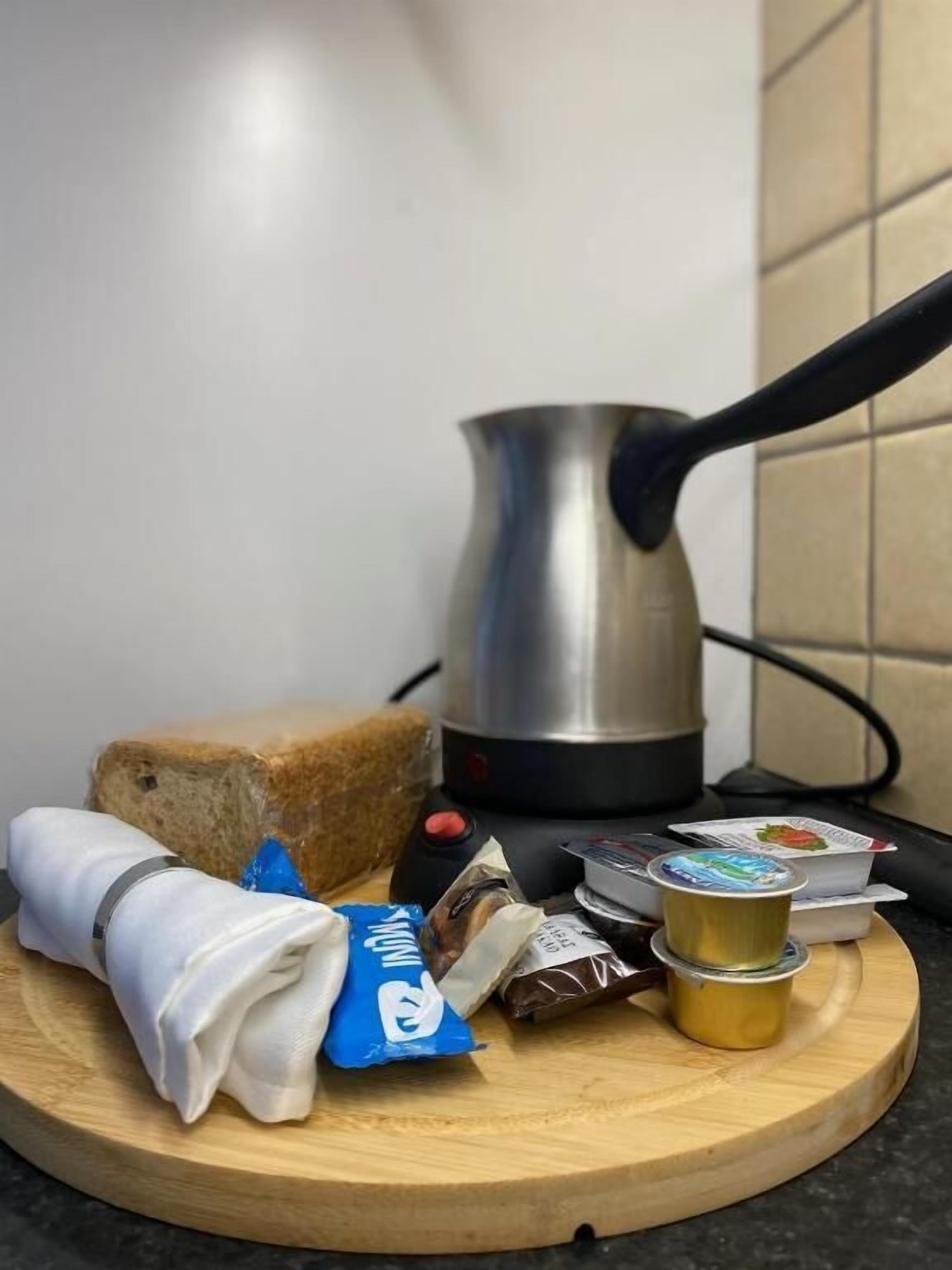 Una encimera de cocina con una barra de pan, una cafetera y diversos alimentos envasados.