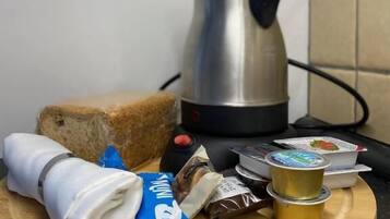 Una encimera de cocina con una barra de pan, una cafetera y diversos alimentos envasados.