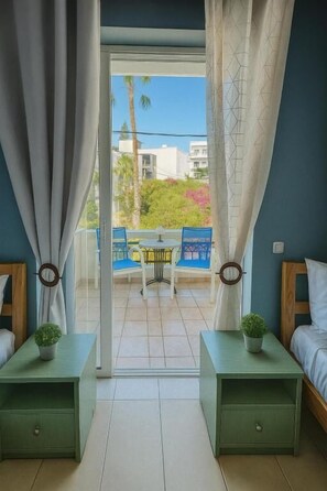 A room with a balcony, a bed, a nightstand with a plant, and a chair. - Rethymno Blue Residence (Rethymno)