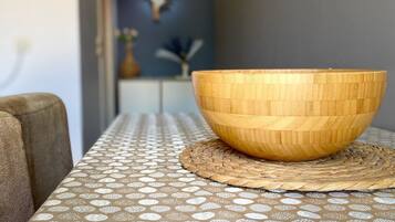 A wooden bowl on a woven placemat on a table with a patterned tablecloth.
