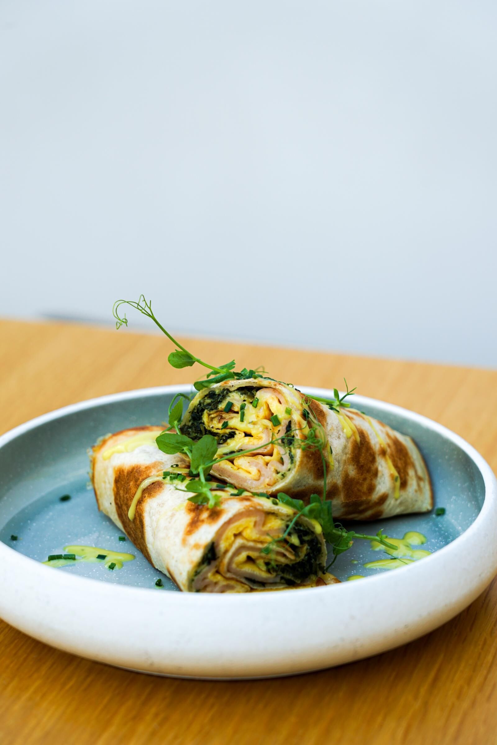 A plate with a rolled food item, garnished with green herbs.