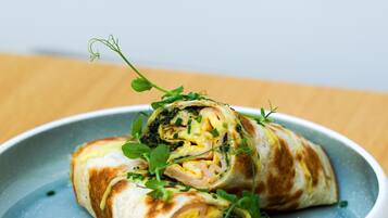 A plate with a rolled food item, garnished with green herbs.