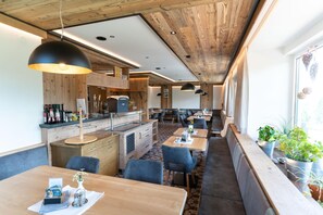 A restaurant with wooden ceiling and walls, tables with chairs, and a bar area.