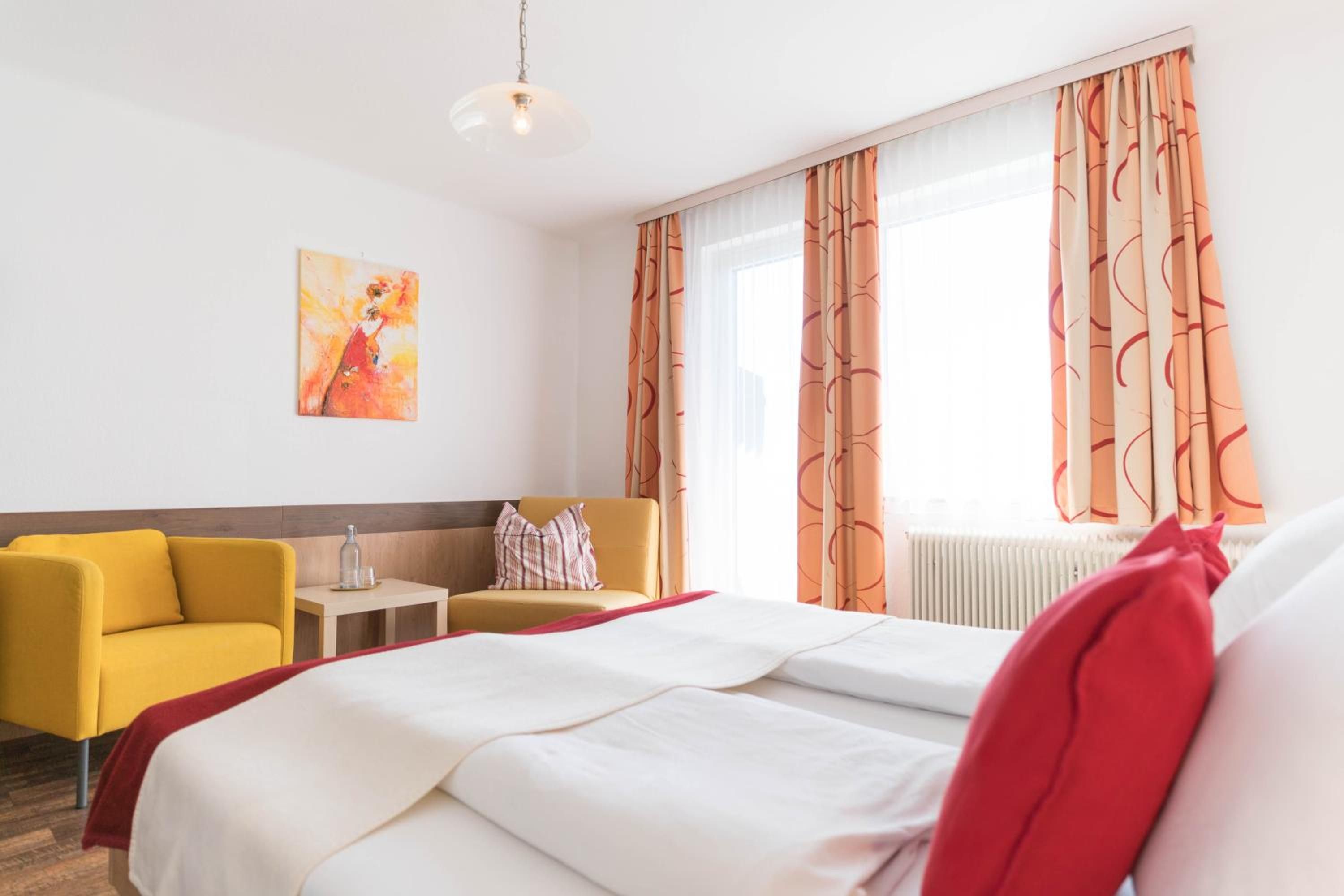 Ein Hotelzimmer mit einem Bett, einem gelben Sessel, einem kleinen Tisch und einem Gemälde an der Wand.