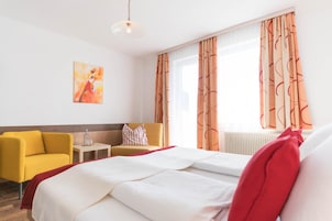 Una habitación de hotel con una cama, un sillón amarillo, una mesita y un cuadro en la pared.