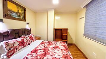 A bedroom with a bed, a nightstand, a wardrobe, and a painting on the wall.