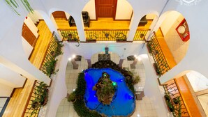 A spacious atrium with a central water feature, wooden flooring, and a balcony with a view of the water. - Hotel David (Quito)