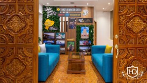 A lobby with a wooden decorative door, two blue sofas, a coffee table, and a signboard with tourist information. - Hotel David (Quito)