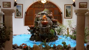 A fountain with birds and a water feature in front of a wooden archway with the text "HOTEL DAVID". - Hotel David (Quito)