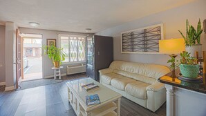 A living room with a sofa, a coffee table, a lamp, and two potted plants. - Liberty Inn And Suites Orlando - Kissimmee Near Disney World (Kissimmee)