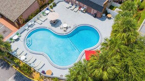 An aerial view of a swimming pool with lounge chairs and tables, surrounded by palm trees and a building. - Liberty Inn And Suites Orlando - Kissimmee Near Disney World (Kissimmee)