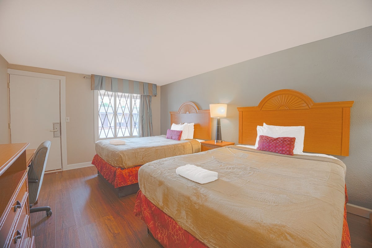 Ein Hotelzimmer mit zwei Betten, einem Schreibtisch und einem Stuhl.