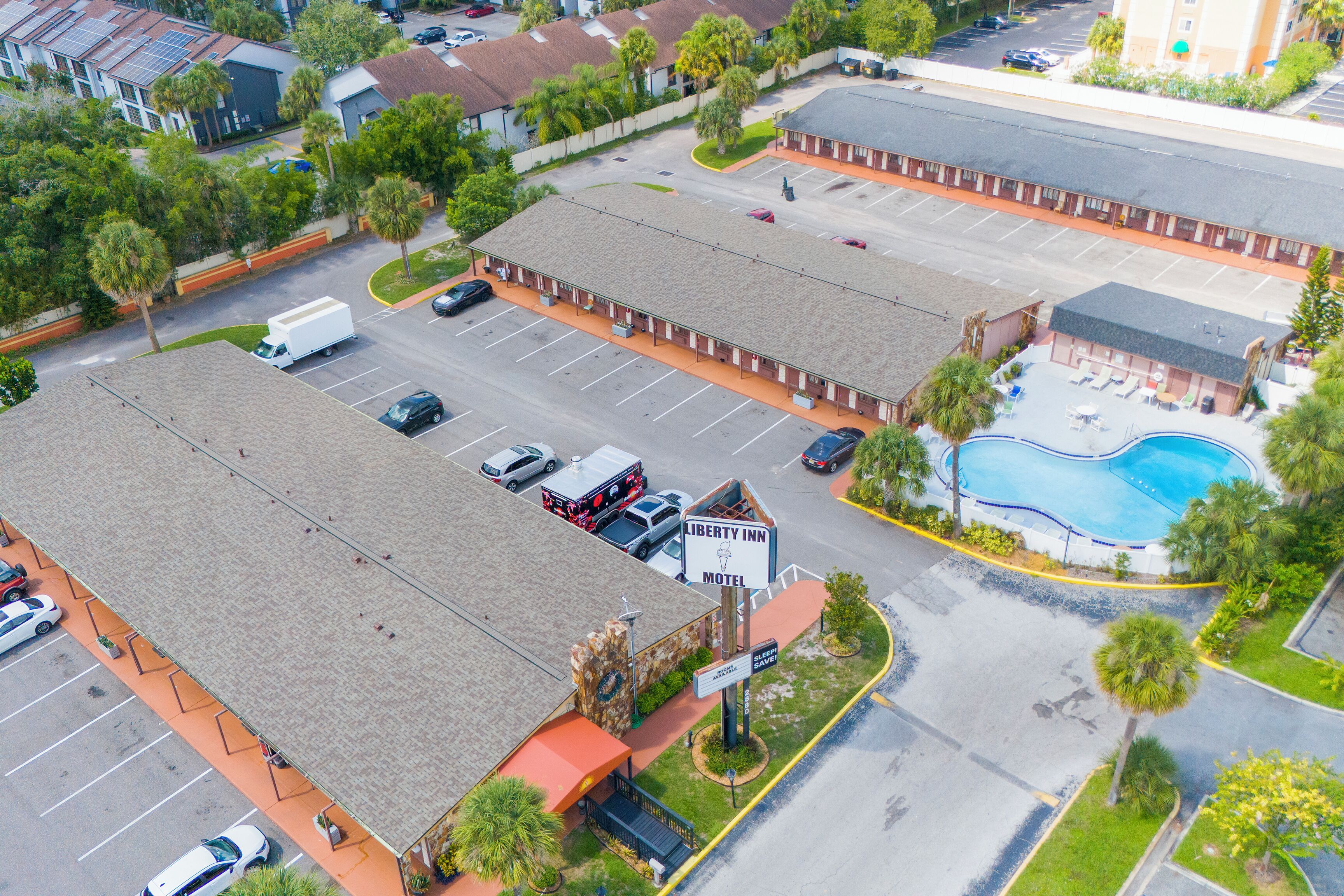 A motel with a swimming pool, multiple parking spaces, and a street view.