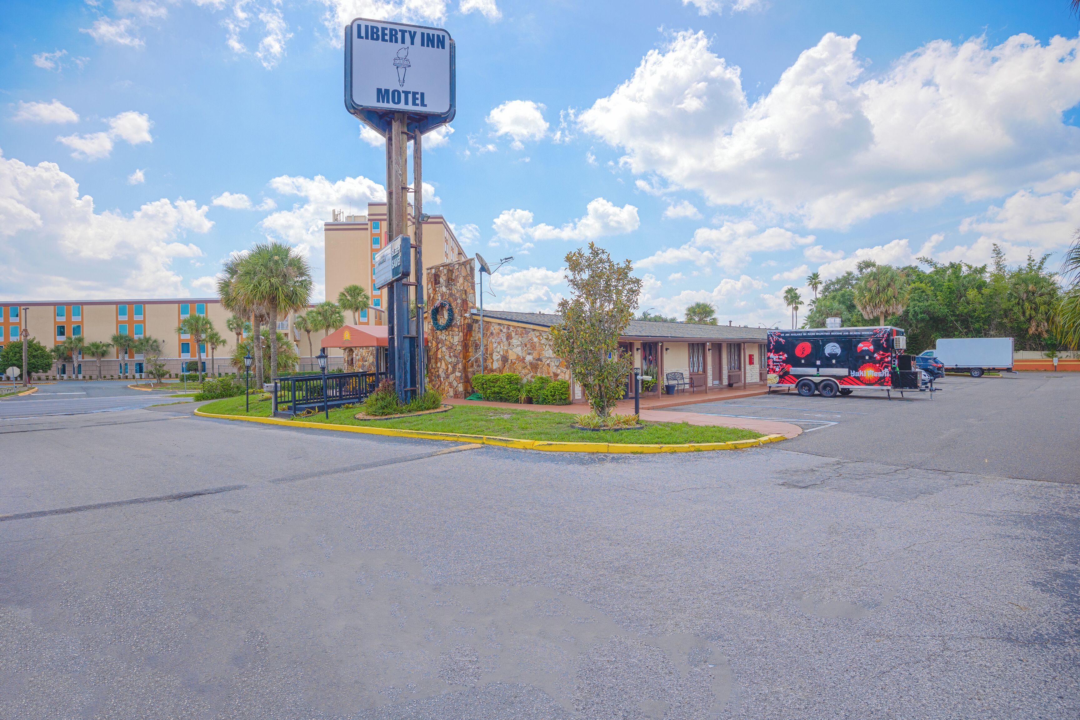 A motel sign, a building with a stone facade, and a parked tour bus.