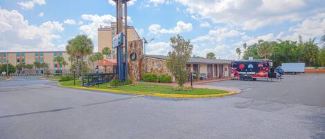 A motel sign, a building with a stone facade, and a parked tour bus.