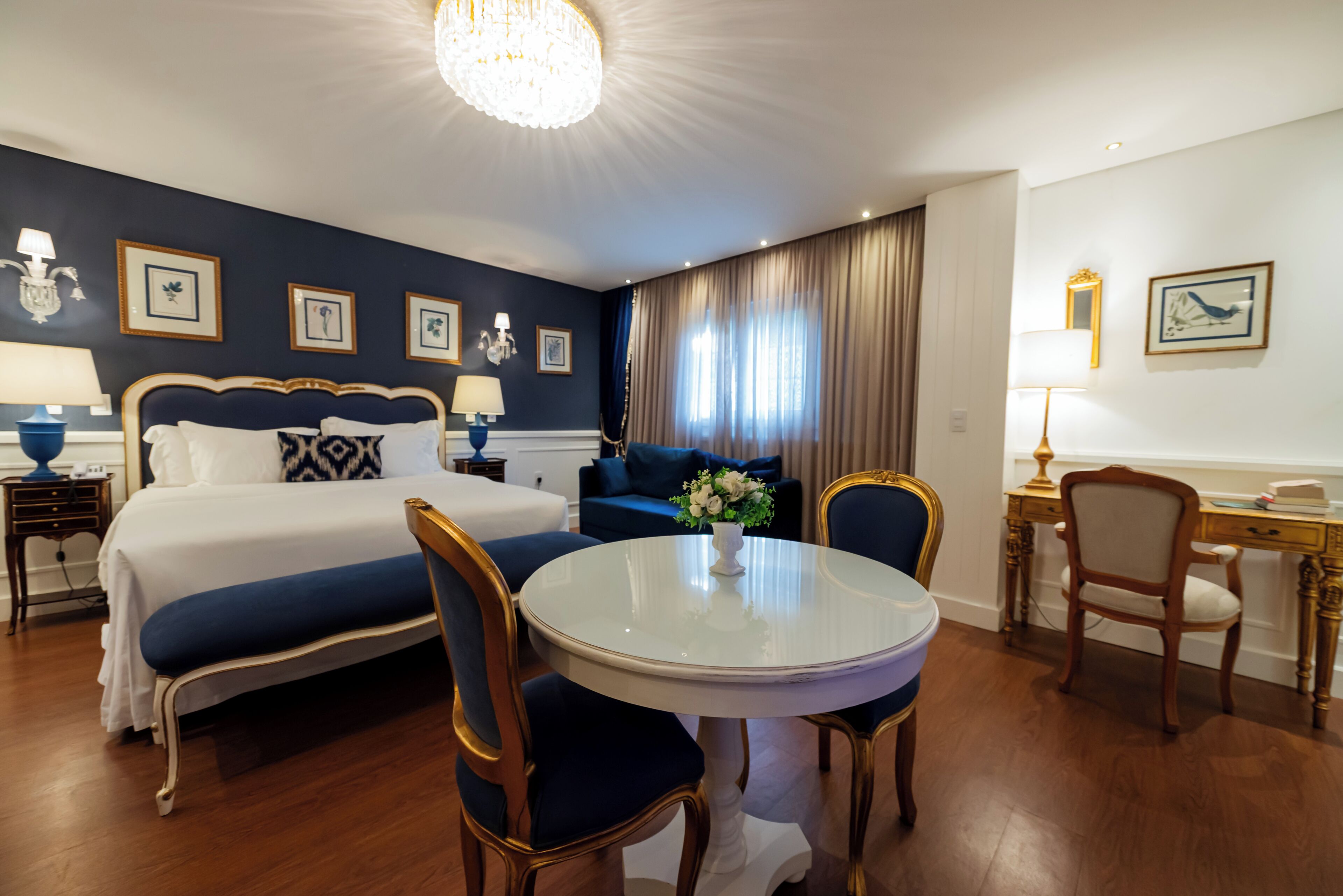 A hotel room with a bed, a round dining table, a desk, and a chair.