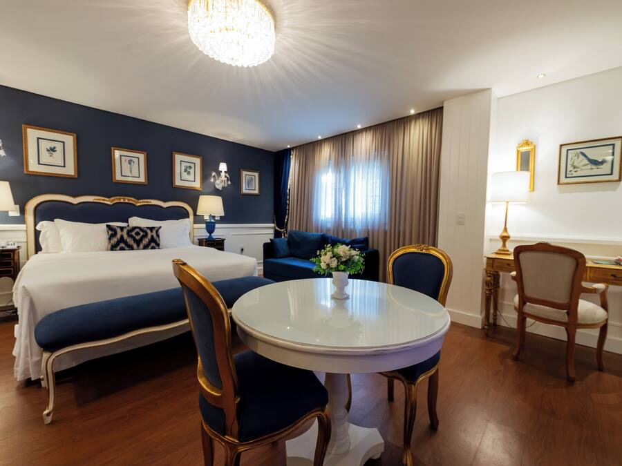 A hotel room with a bed, a round dining table, a desk, and a chair.