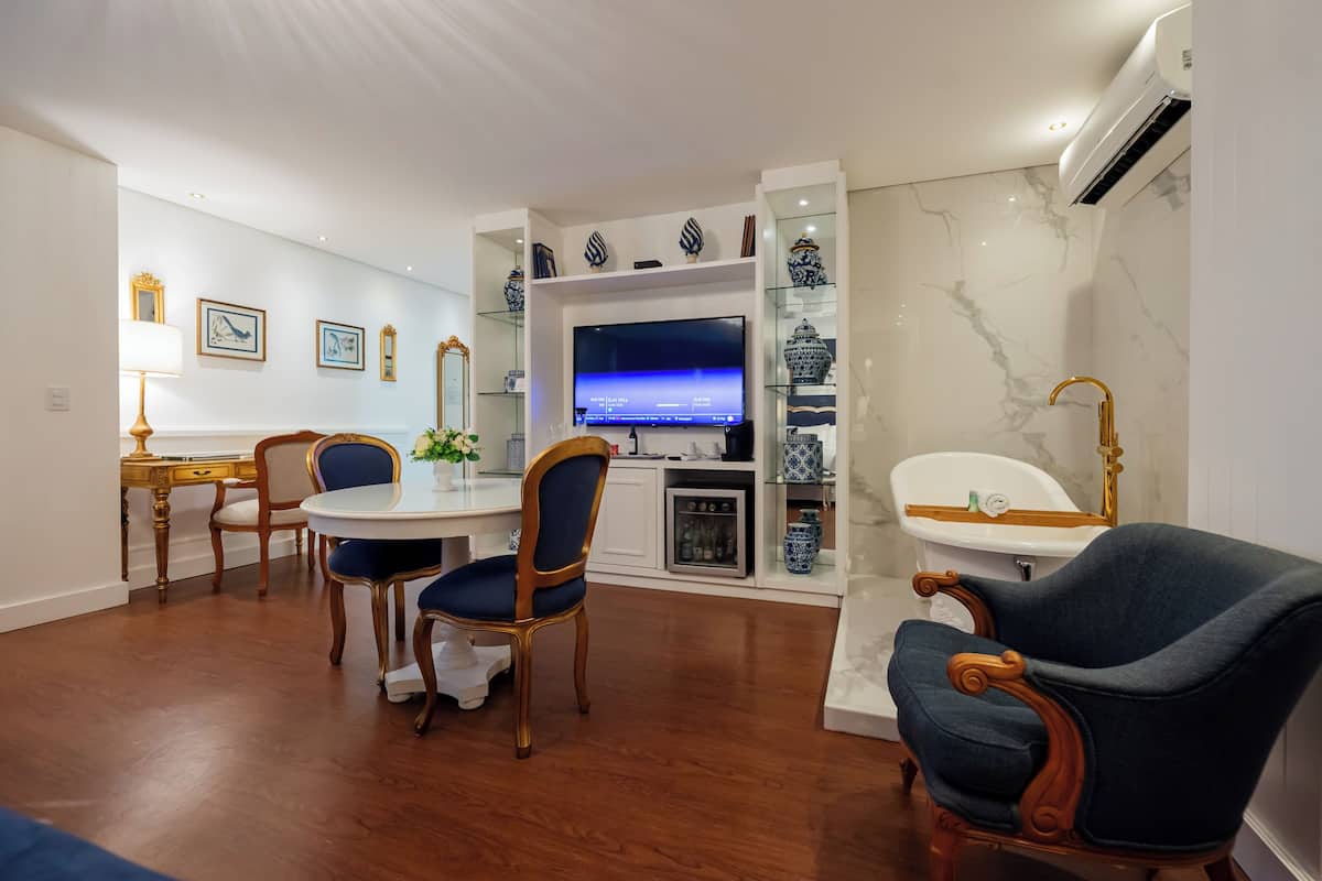 Una sala de estar moderna con comedor, televisor y baño con bañera y lavabo.