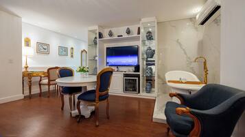 Una sala de estar moderna con comedor, televisor y baño con bañera y lavabo.