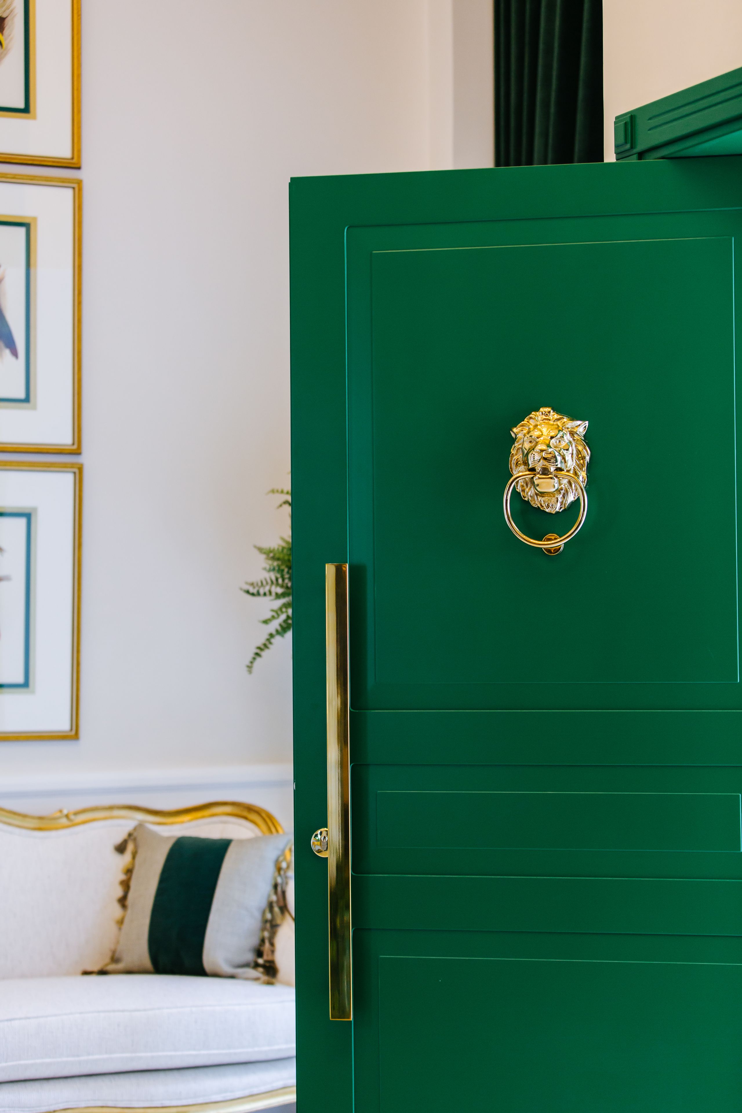 Una puerta verde con un tirador dorado con forma de cabeza de león.