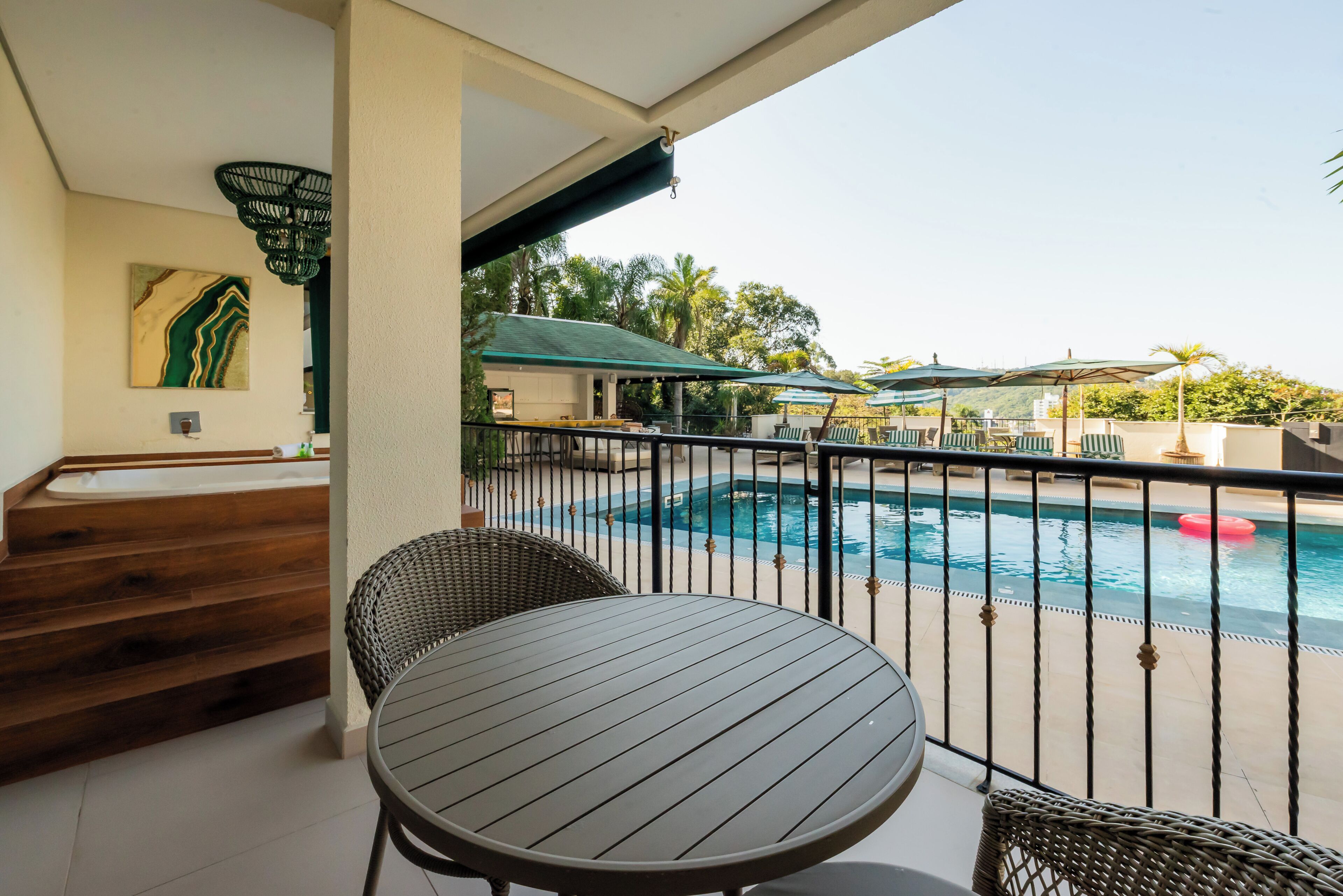 A balcony with a pool, wicker furniture, and a painting on the wall.