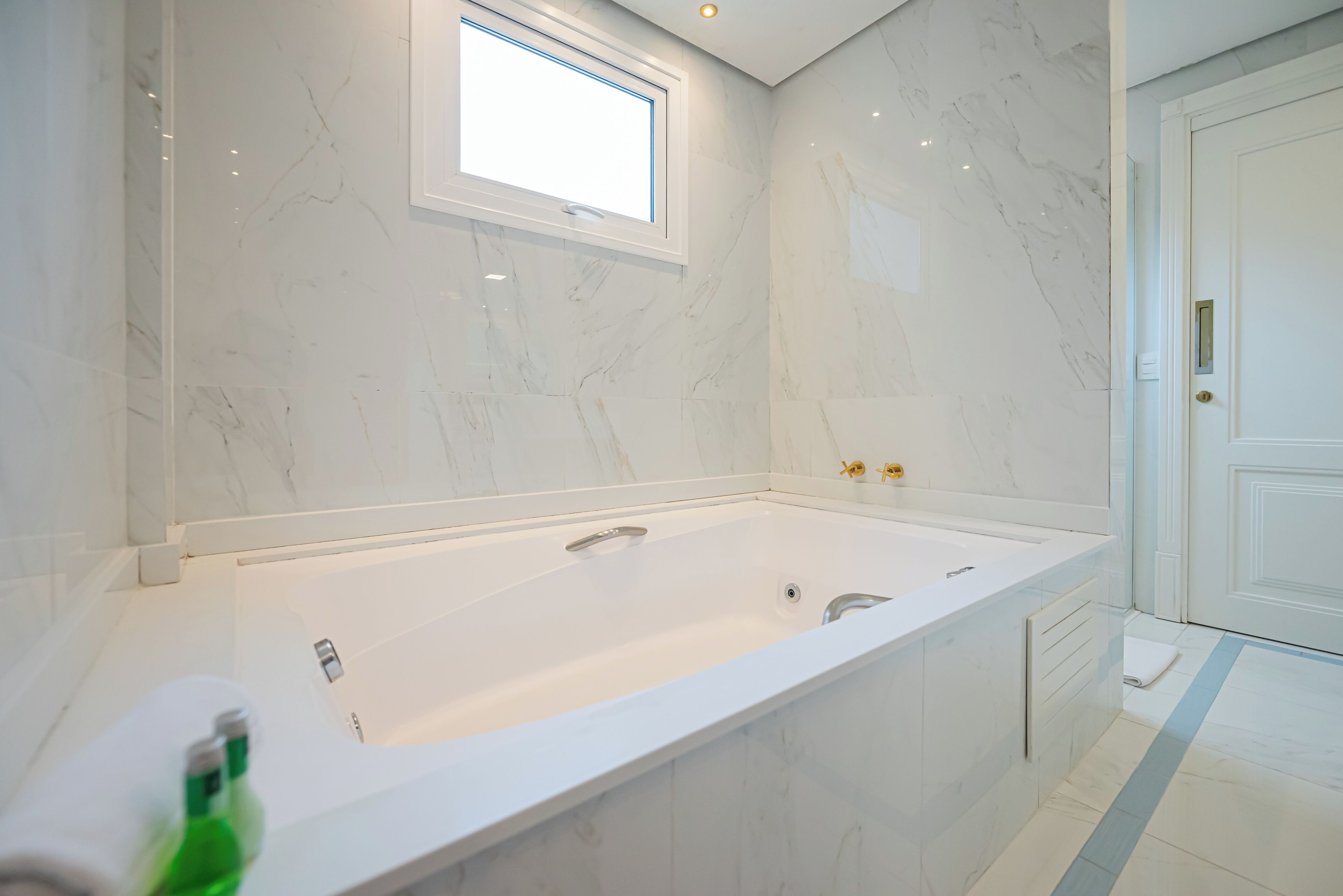 Un baño moderno con una bañera grande, una ventana y una puerta.