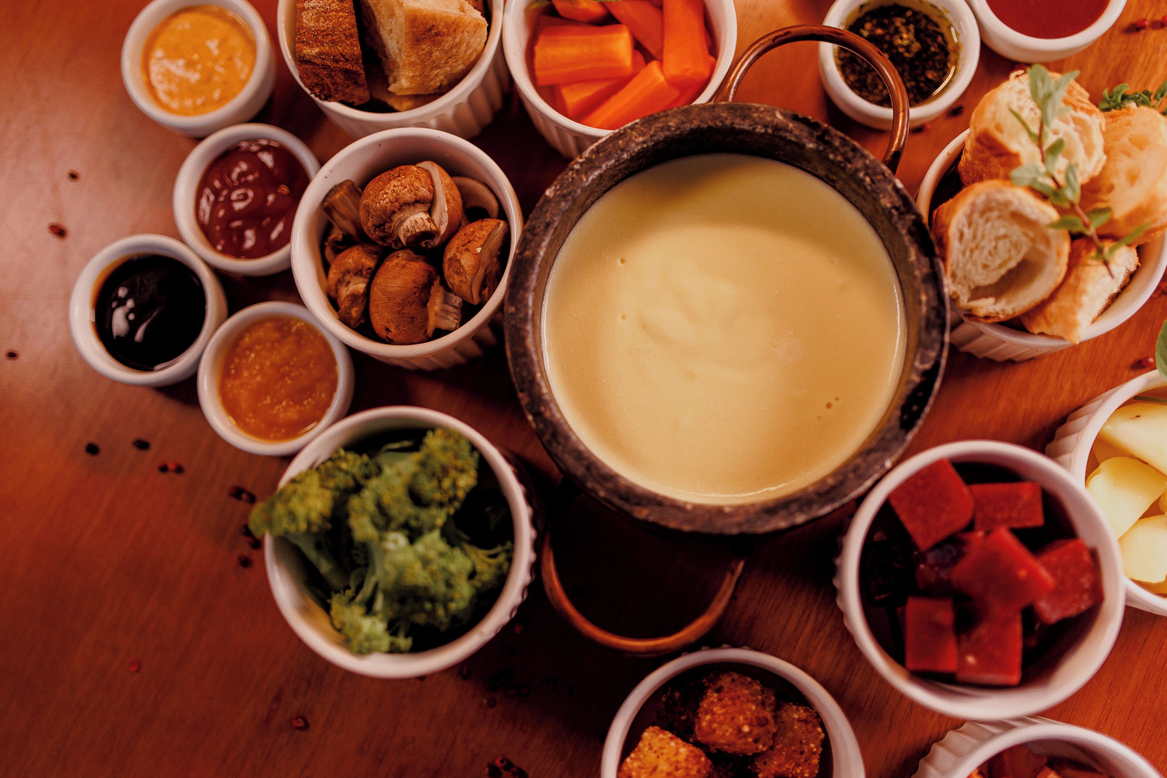 A variety of food items including a large bowl of soup, several small bowls of condiments, and some bread.