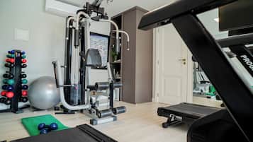 Un gimnasio en casa con equipo de ejercicio, una cinta de correr y un espejo que refleja la habitación.