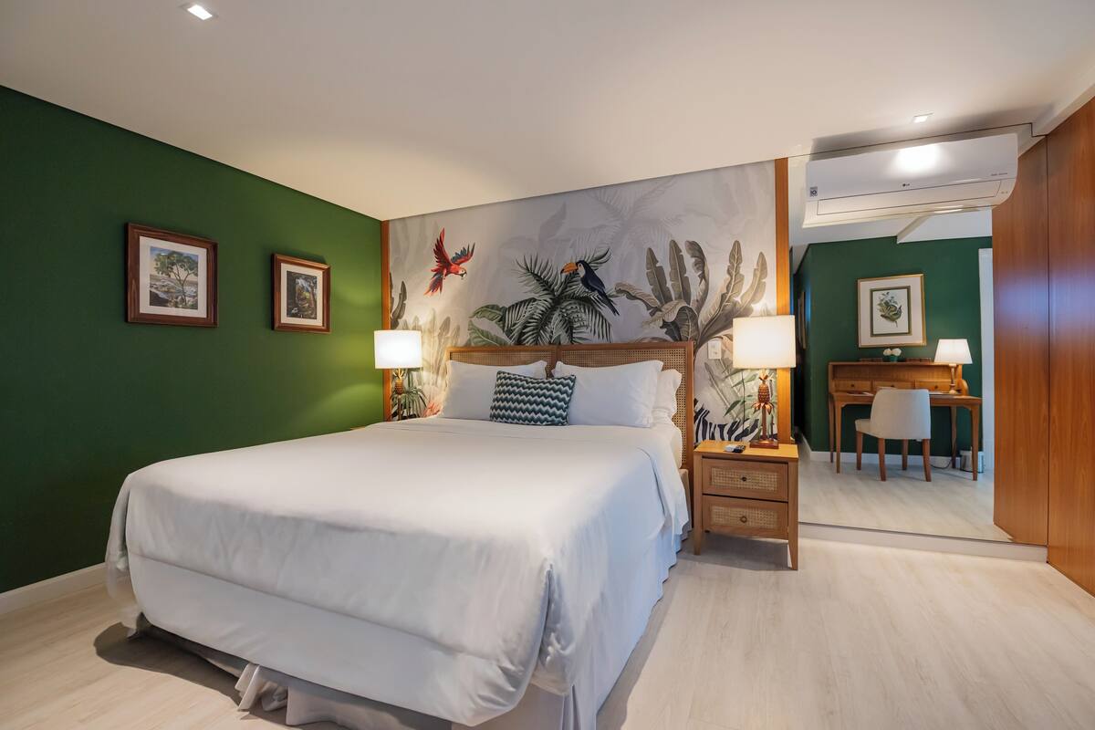 Una habitación de hotel con una cama grande, un escritorio, una silla y una pared con un mural.