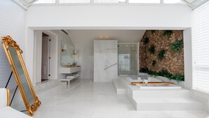 Un baño moderno con piso de mármol, un espejo grande y una pared de piedra con plantas.