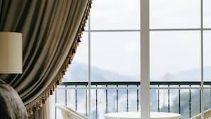 Habitación de hotel con balcón, una cama, una mesa redonda y vistas a las montañas.