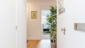 Un couloir étroit avec un plancher en bois, des murs blancs et une plante en pot.
