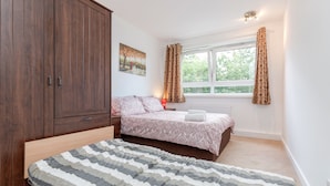 Une chambre avec une grande armoire, deux lits, une fenêtre avec des rideaux et un radiateur.