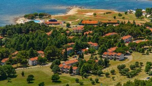 An aerial view of a coastal residential area with houses, a swimming pool, and a beach.