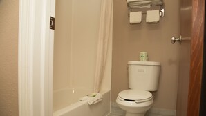 A bathroom with a bathtub, toilet, and a towel rack with towels. - Executive Inn (Indianapolis)