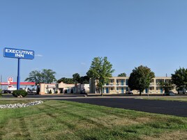 Un hotel llamado Executive Inn, con un letrero, una estación de servicio y un edificio con varias ventanas y balcones.