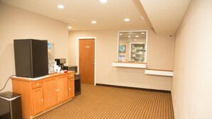 A hotel room with a kitchenette, a refrigerator, a microwave, a trash bin, and a wooden cabinet. - Executive Inn (Indianapolis)
