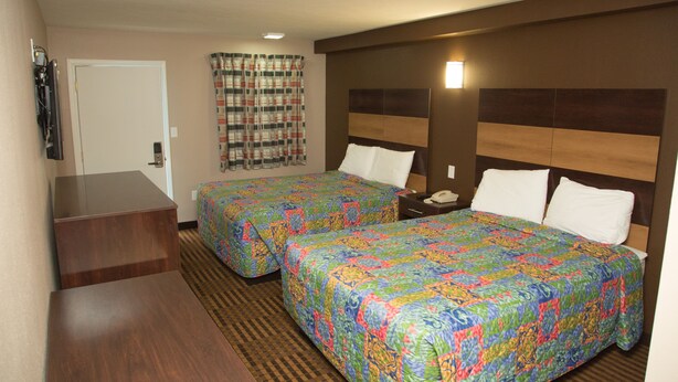 A hotel room with two beds, a desk, a chair, a TV, and a bathroom door. - Executive Inn (Indianapolis)
