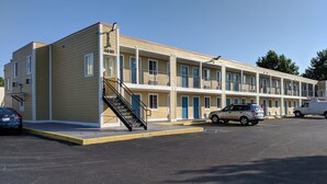 A motel with a two-story structure, a covered parking area, and a staircase leading to the entrance. - Executive Inn (Indianapolis)