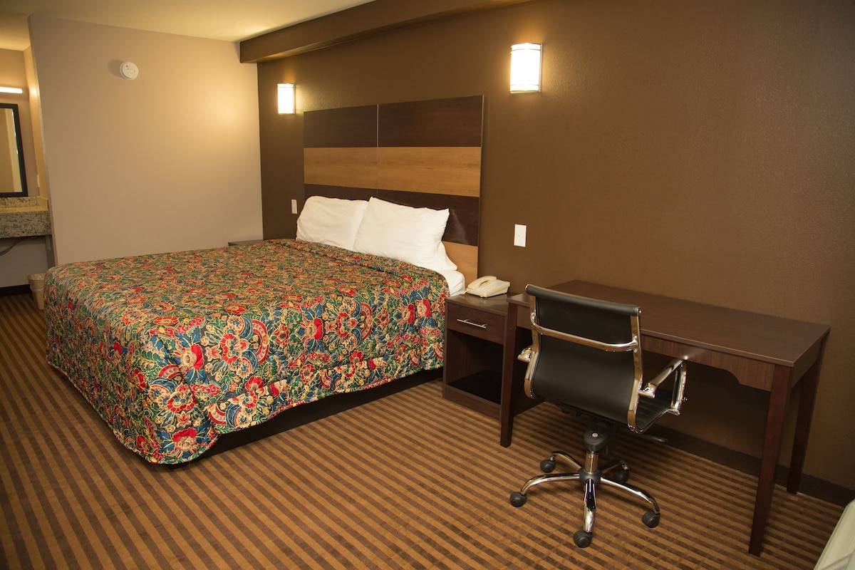 Una habitación de hotel con una cama grande, un escritorio, una silla y un teléfono.