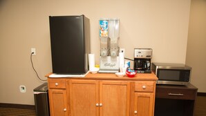 A kitchenette with a refrigerator, coffee maker, microwave, and a beverage dispenser. - Executive Inn (Indianapolis)
