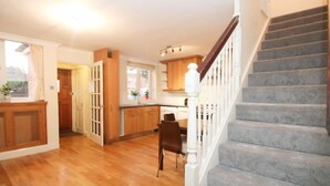 Eine geräumige Küche mit Holzausbau, ein Essbereich mit einem Stuhl und eine Treppe mit hölzernem Geländer.