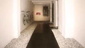 A hallway with bicycles mounted on the wall, a black floor, and a gravel path. - Agrado Guest House (Oaxaca)