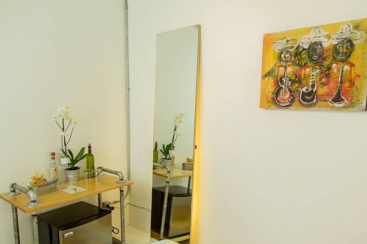 A bathroom with a mirror, sink, and a painting on the wall.