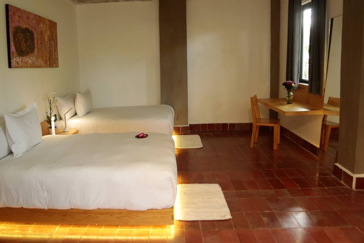 A hotel room with two beds, a desk, and a chair.