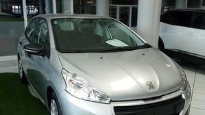 A silver car parked inside a building with a tiled floor and a green carpeted area. - Au Regina (Arue)