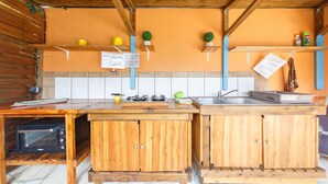 A compact kitchen with wooden cabinets, a built-in oven, a sink, and a small countertop. - Au Regina (Arue)