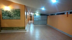 A corridor with tiled flooring, a green patterned wall, and a blue storage unit. - Au Regina (Arue)