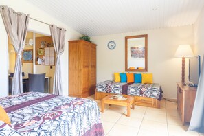 Una habitación con dos camas, un armario de madera, una mesita, un televisor y un espejo en la pared.